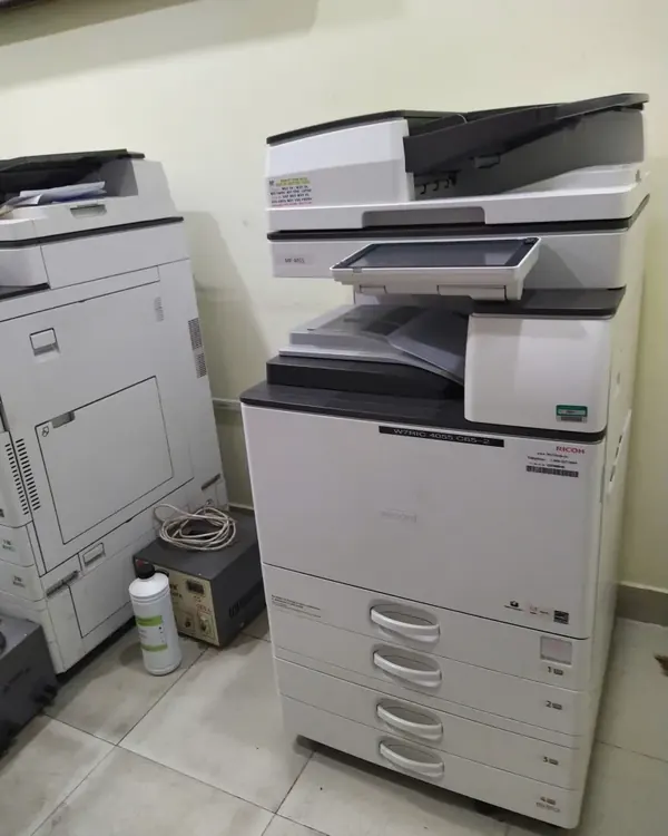M&aacute;y photocopy Ricoh cho thu&ecirc; đặt cạnh m&aacute;y kh&aacute;c trong ph&ograve;ng in của kh&aacute;ch h&agrave;ng